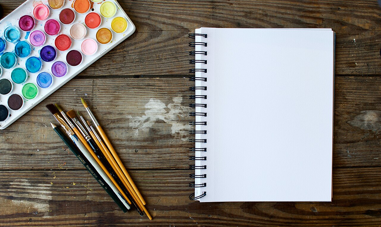Illustrative photograph: A notebook and paint brushes